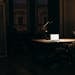 A man working late at night in a dimly lit office, with a bright laptop screen.